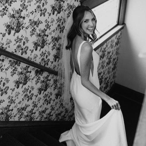 Bride looks back at the camera while walking down staircase