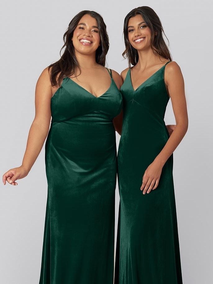 Two models wear Kennedy Blue velvet bridesmaid dresses in the color emerald