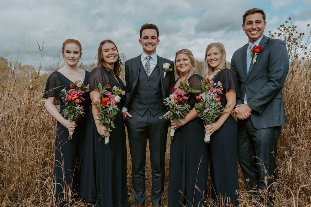 Bridal party wears navy bridesmaid dresses and suits